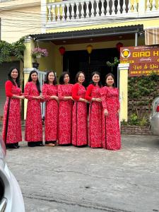 Eine Gruppe von Frauen in roten Kleidern, die für ein Bild posieren in der Unterkunft Giao Hòa Homestay Hội An in Hoi An