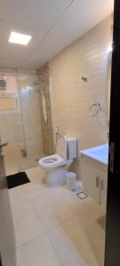 een badkamer met een toilet, een douche en een wastafel bij Al Nujoom Apartment, Al Qurum in Wuţayyah
