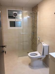 een badkamer met een douche, een toilet en een glazen deur bij Al Nujoom Apartment, Al Qurum in Wuţayyah