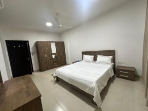 een slaapkamer met een groot wit bed en een deur bij Al Nujoom Apartment, Al Qurum in Wuţayyah