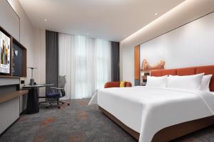 a hotel room with a large bed and a desk at Hampton by Hilton Wuhan Optics Valley in Wuhan