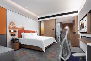 a hotel room with a white bed and a chair at Hampton by Hilton Wuhan Optics Valley in Wuhan