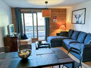 Appartement Valmorel, 3 pièces, 7 personnes - FR-1-356-414 في فالموريل: غرفة معيشة مع أريكة زرقاء وطاولة