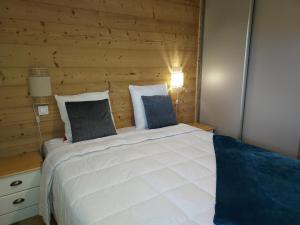 um quarto com uma grande cama branca e uma parede de madeira em Appartement Valmorel, 2 pièces, 4 personnes - FR-1-356-423 em Valmorel