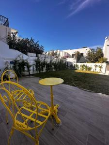 une table et des chaises jaunes sur une terrasse dans l'établissement App avec jardin dans un hôtel, à Gammarth