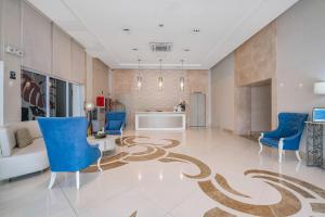 a living room with blue chairs and a carpet on the floor at Tess and Tessha Condotel in Manila