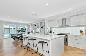 - une cuisine blanche avec un grand îlot et des tabourets de bar dans l'établissement Putt Putt - Pool Slide - 100m to Beach - Ultimate Family Entertainer, à Kingscliff