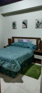 um quarto com uma cama com um edredão azul e uma secretária em Guango Grove Cozy Corner em Montego Bay