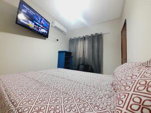 a bedroom with a bed and a flat screen tv at APARTAMENTO - 2 quartos in Campo Grande