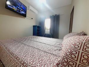 um quarto com uma cama e uma TV na parede em 2 quartos com ar - Apto em condomínio em Campo Grande