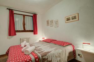 1 dormitorio con 1 cama con sábanas rojas y toallas blancas en Paquita's Home - San Sicario Borgo - Happy Rentals en Cesana Torinese