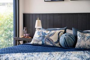 uma cama com almofadas azuis e brancas e um candeeiro em Hyams Beach House B - Brand new lux beach oasis em Hyams Beach