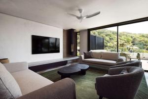 a living room with couches and a flat screen tv at Moonrise & Starfall in Byron Bay