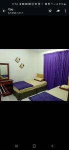 two beds in a room with purple curtains at Homestay Rose Guest House 2.0 in Gambang