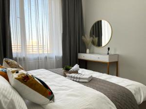 Schlafzimmer mit einem großen weißen Bett und einem Spiegel in der Unterkunft 3х-комнатная квартира бизнес класса in Almaty