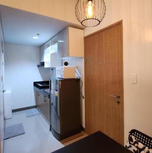a small kitchen with a refrigerator and a door at Bloom Residences Condo 2Br in Manila