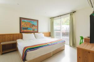 a bedroom with a bed with a painting on the wall at LowPressure Surf Guesthouse in Donghe