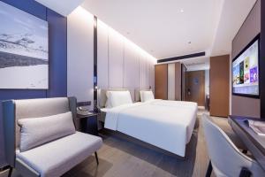 una camera con un letto bianco e due sedie di Atour Hotel Shenzhen Huaqiangbei Commercial Center a Shenzhen