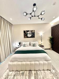 a bedroom with a large white bed with a chandelier at Harbour View Condo - Seaview اطلالة بحرية in Manama