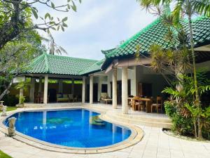 a villa with a swimming pool in front of a house at Bali Jade Villas in Sanur