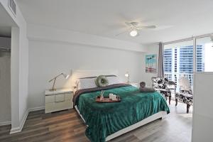 a white bedroom with a green bed and a table at Upscale Apartment in the Heart of Brickell in Miami