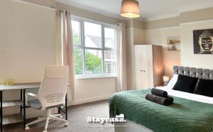 a bedroom with a bed and a desk and a window at Homely 4-bedroom House in Manchester