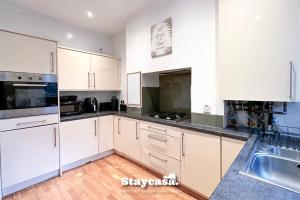 a kitchen with white cabinets and a sink at Homely 4-bedroom House in Manchester