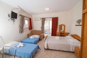 een hotelkamer met 2 bedden en een bank bij Rooms Nancy in Áyios Andréas Messinias