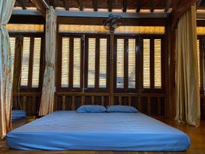 a large bed in a room with windows at Homestay-Nhà Sàn Ngán Chải in Ha Giang