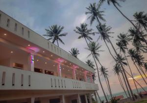 un edificio con palmeras en el fondo en Eventide Beach Resort en Marawila