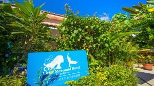 ein Schild für das Meerjungfrauenhotel mit Pflanzen in der Unterkunft Little Mermaid Hotel Ishigakijima in Ishigaki-jima