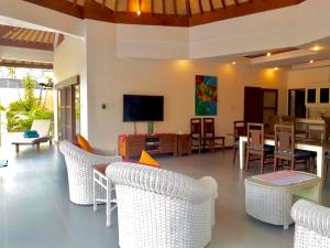 uma sala de estar com cadeiras brancas e uma televisão em Bali Jade Villas em Sanur