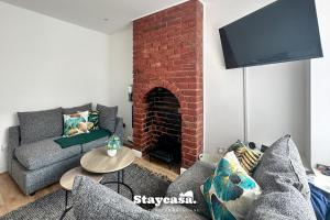 a living room with a couch and a brick fireplace at Stunning 3bdr 2ba House With Free Street Parkin in Birmingham