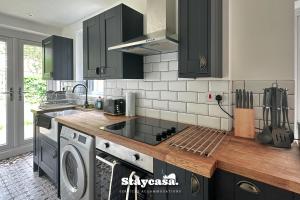 a kitchen with black cabinets and a washer and dryer at Stunning 3bdr 2ba House With Free Street Parkin in Birmingham