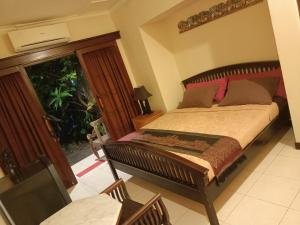 a bedroom with a bed and a glass door at Villa Layang Bulan - Male Only in Denpasar