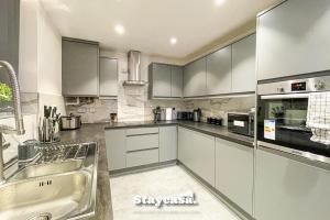 a kitchen with white cabinets and a sink at Live In Style House In Desirable Location in Manchester