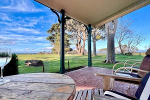 a patio with a table and chairs and a view of a field at Farmhouse Charm - Coastal Comforts and Country Views in Cowes