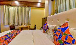 een slaapkamer met een groot bed en een kleurrijk dekbed bij FabHotel Raj Palace I in Vadodara