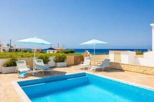 a swimming pool with chairs and umbrellas on a house at Villa Diana Seaside in Pomos