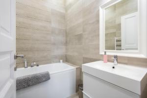 W białej łazience znajduje się umywalka i lustro. w obiekcie Luxury 3BEDRM 2BATHRM Apartment with Danube River View w Budapeszcie