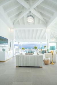 una sala de estar blanca con un sofá blanco y el océano en La Perla Bianca - 1 BR Beachfront Luxury Villa offering utmost privacy en Les Terres Basses