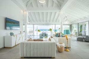 una sala de estar blanca con un sofá blanco y sillas en La Perla Bianca - 1 BR Beachfront Luxury Villa offering utmost privacy en Les Terres Basses