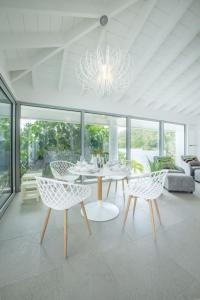 sala de estar con mesa, sillas y lámpara de araña en La Perla Bianca - 1 BR Beachfront Luxury Villa offering utmost privacy en Les Terres Basses