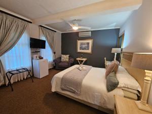 een hotelkamer met een groot bed en een stoel bij Hillton Manor Guest House in Richards Bay