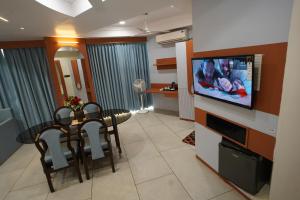 HOTEL GOKUL في غانديدام: غرفة معيشة مع طاولة طعام وتلفزيون بشاشة مسطحة