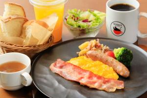 a plate of food with a breakfast of eggs sausage and bread at Richmond Hotel Yokohama-Bashamichi in Yokohama