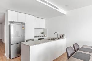 uma cozinha com armários brancos e um frigorífico de aço inoxidável em Shellharbour Lakeview Apartment em Barrack Point