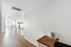 un couloir avec des murs blancs et une table en bois dans l'établissement Shellharbour Lakeview Apartment, à Barrack Point