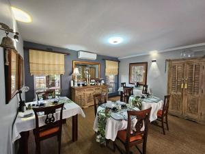 a dining room with two tables and chairs and a kitchen at Hillton Manor Guest House in Richards Bay