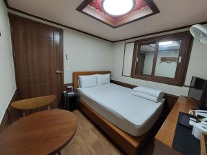 Prince Motel في بوسان: غرفة نوم صغيرة مع سرير وطاولة